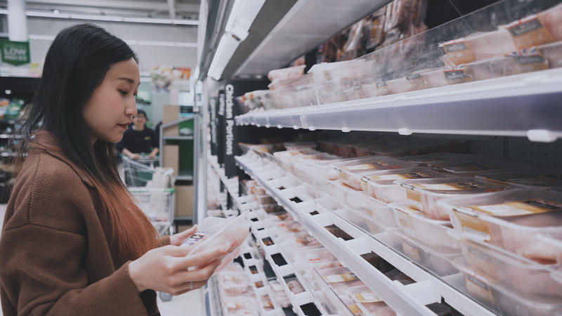 Woman holding packaged chicken in supermarket